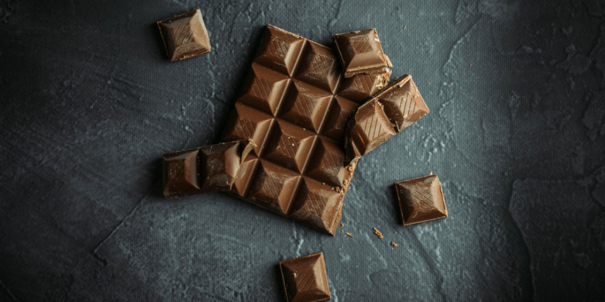 Eine halbe Tafel Schokolade liegt auf dem Tisch mit Stückchen drum herum